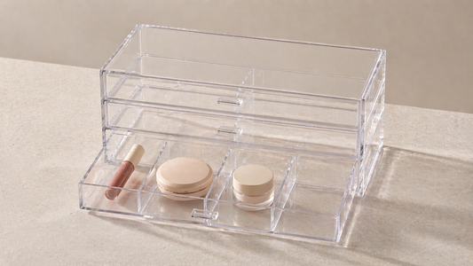 Minimal clear acrylic drawer organizer with items separated by category and one empty space, showing an efficient layout that needs no additional items.