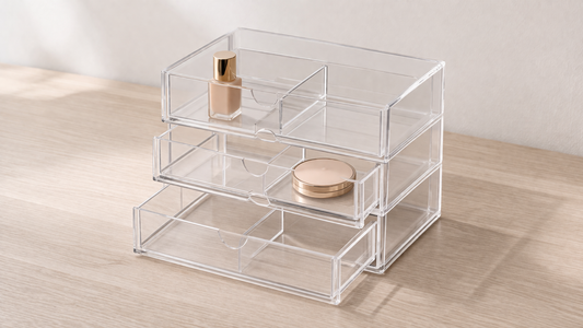 Transparent acrylic drawer organizer with built-in dividers separating items across layered drawers for structured deep storage