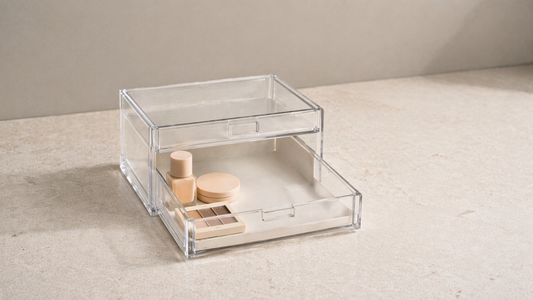 Compact acrylic drawer with a small cluster of makeup items in one corner and wide empty space to improve small drawer usability.