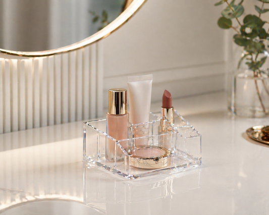 Minimal acrylic makeup organizer with 2–3 items grouped in a defined zone to prevent clutter spread on a small vanity surface.