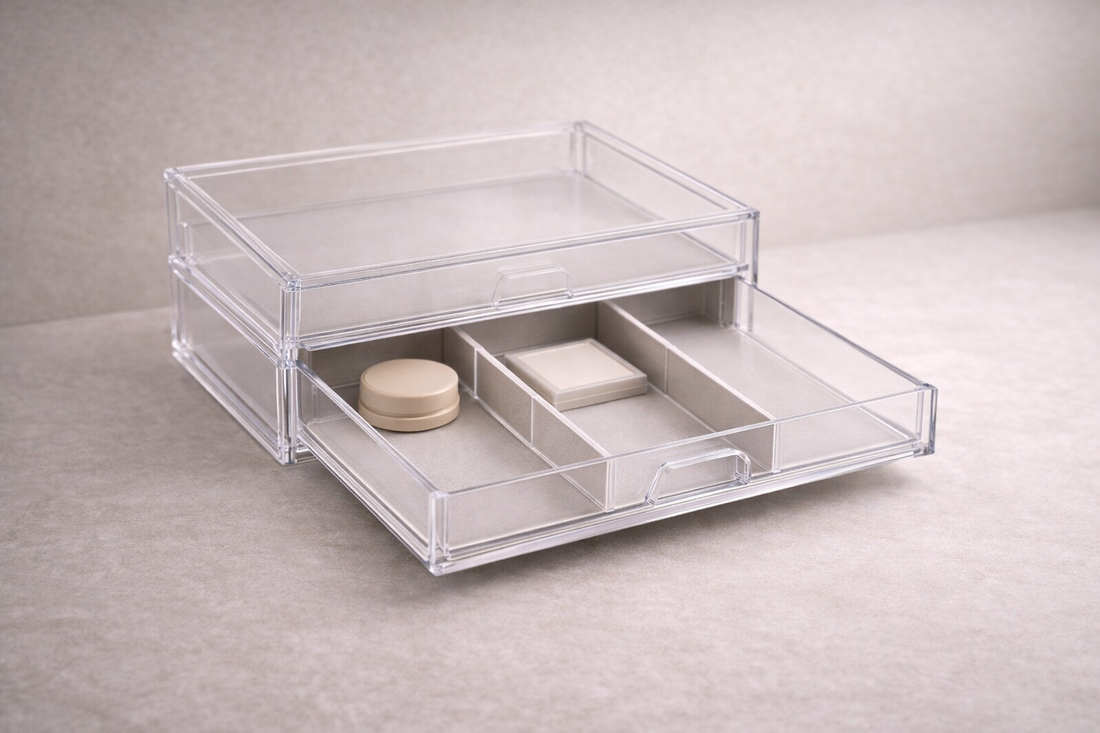Segmented acrylic drawer organizer with three makeup items placed in separate compartments and one empty section for clear structure.