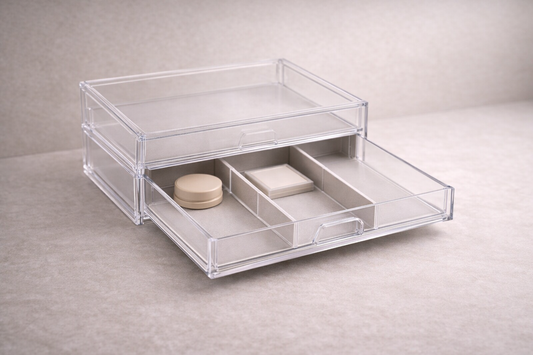 Segmented acrylic drawer organizer with three makeup items placed in separate compartments and one empty section for clear structure.