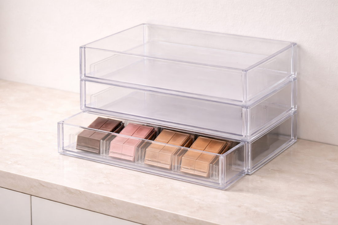 Clear drawer organizer storing eyeshadow palettes vertically with spaced dividers for visibility and protection.