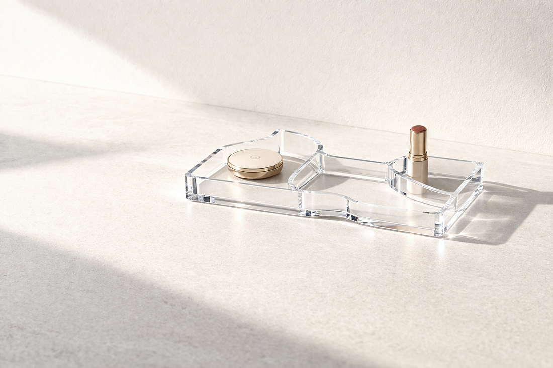 Makeup storage ideas for fast routines that improve daily efficiency featuring a low-profile clear acrylic tray with contoured edges and divided sections holding a powder compact and lipstick