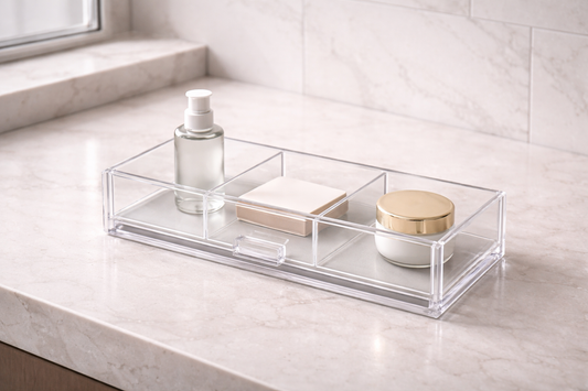 Clear acrylic drawer organizer with three items spaced across compartments, showing smooth reach flow and efficient morning routine layout