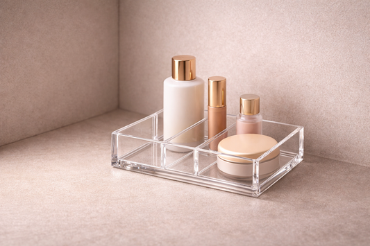 High-end 16:9 horizontal image of a single clear acrylic makeup organizer in a corner setup with four items arranged in a slightly dense layout, showing an efficient one-system structure for daily routines