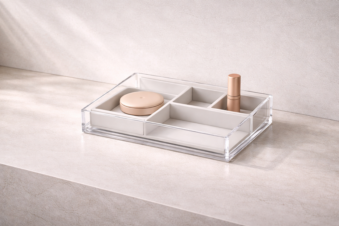 Organized setup for faster mornings that improves daily flow featuring a low-profile clear acrylic tray with grey divided compartments holding cosmetic products on a neutral surface