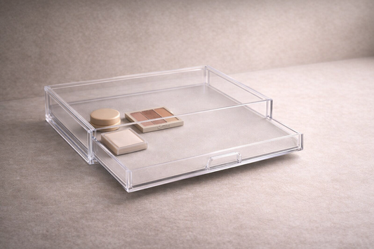 Clear acrylic shallow drawer organizer with three low-profile makeup items and strong empty space for structured access.