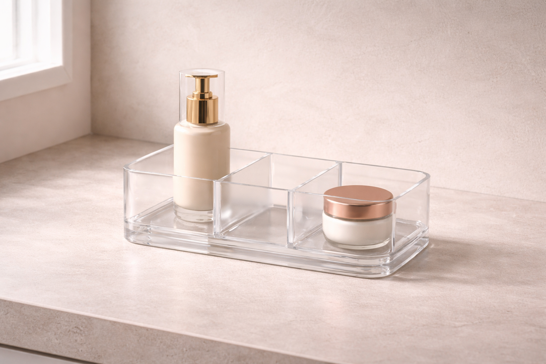 Skincare setup for easier and more consistent routines featuring a clear divided acrylic organizer with a gold-pump bottle and cream jar on a stone countertop