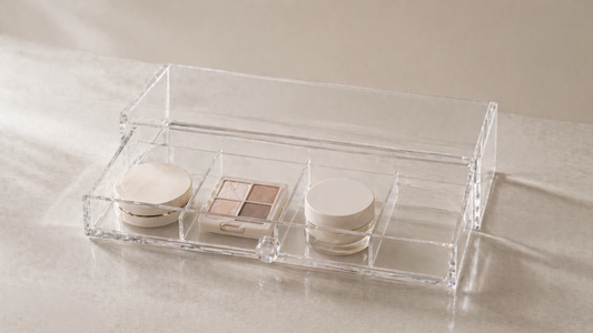 Clear acrylic drawer organizer with visible compartments and fixed item placement, including one empty section, creating a stable layout that remains unchanged over time.