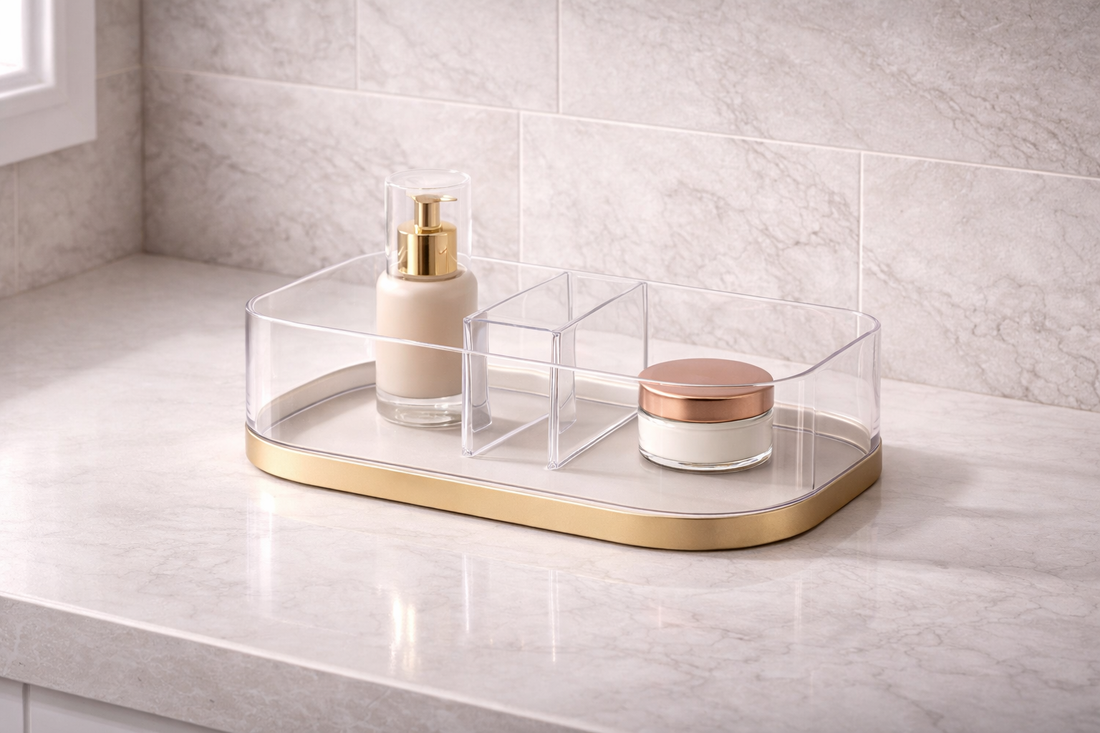 Vanity organization for faster and more streamlined mornings featuring a clear acrylic organizer with a gold base and divided compartments on a marble countertop