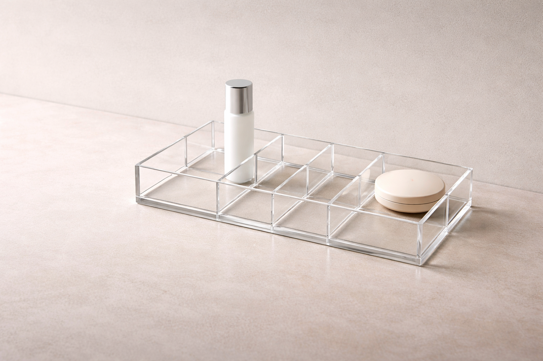 16:8 wide header image of a zoned acrylic vanity layout on a matte stone surface with strong air gaps between items.