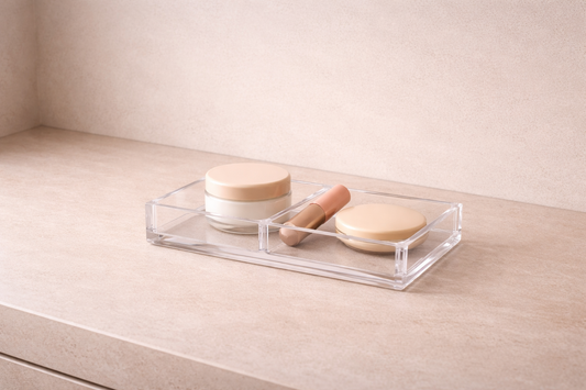 High-end 16:8 horizontal image of a minimal clear acrylic makeup organizer with three loosely placed items, showing a calm and settled makeup space with stable daily routine structure